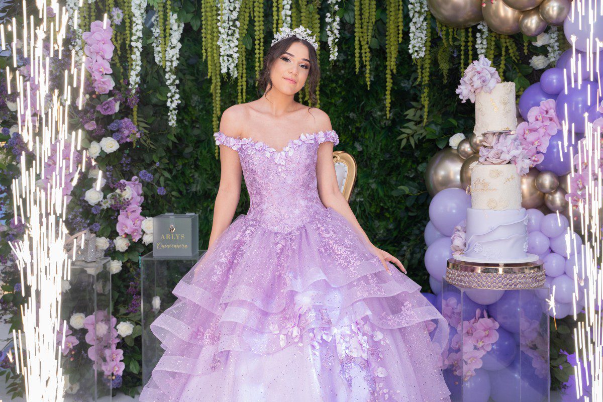 A woman in a purple dress standing next to a cake.