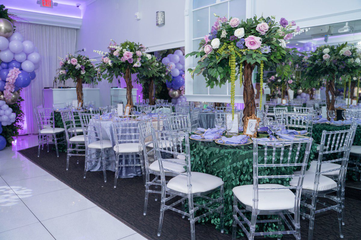 A room with many tables and chairs, decorated in purple.