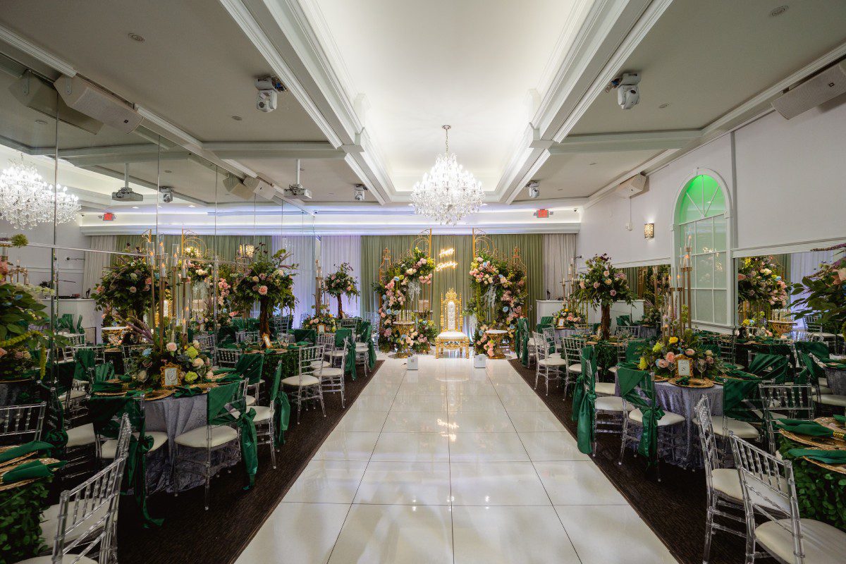 A white aisle with green chairs and tables