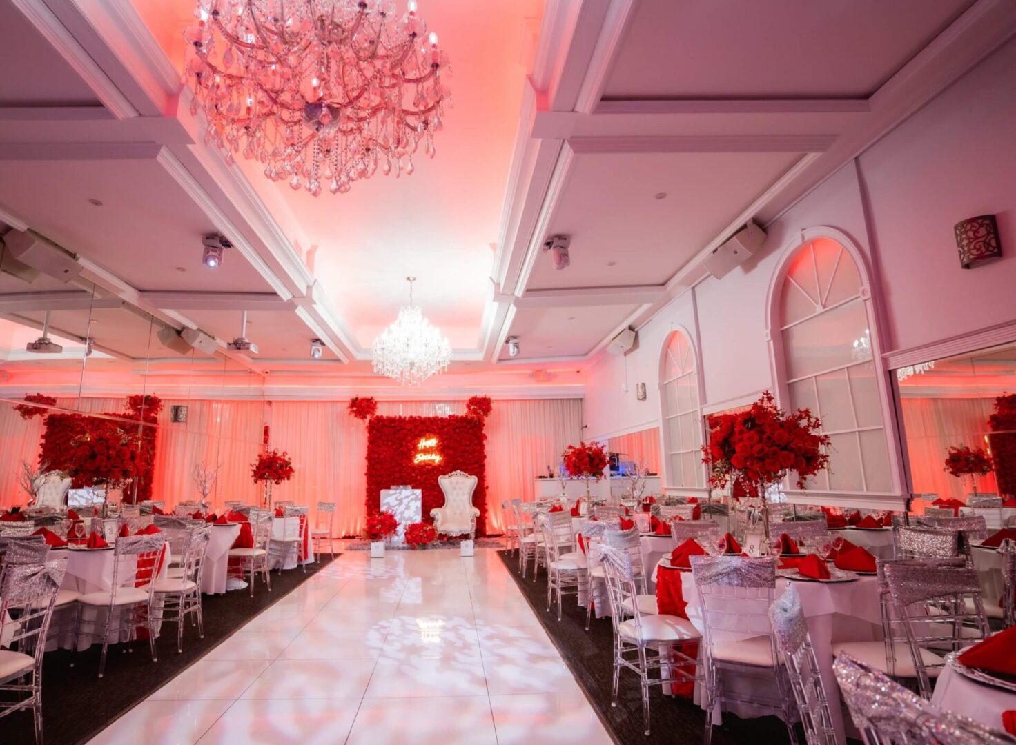 A ballroom with red and white decor and tables.