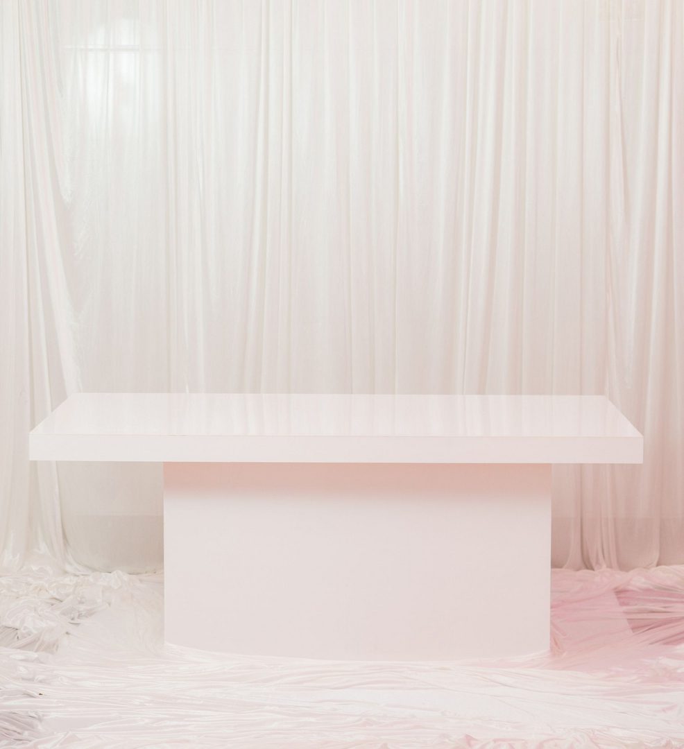 A white table with a pink background