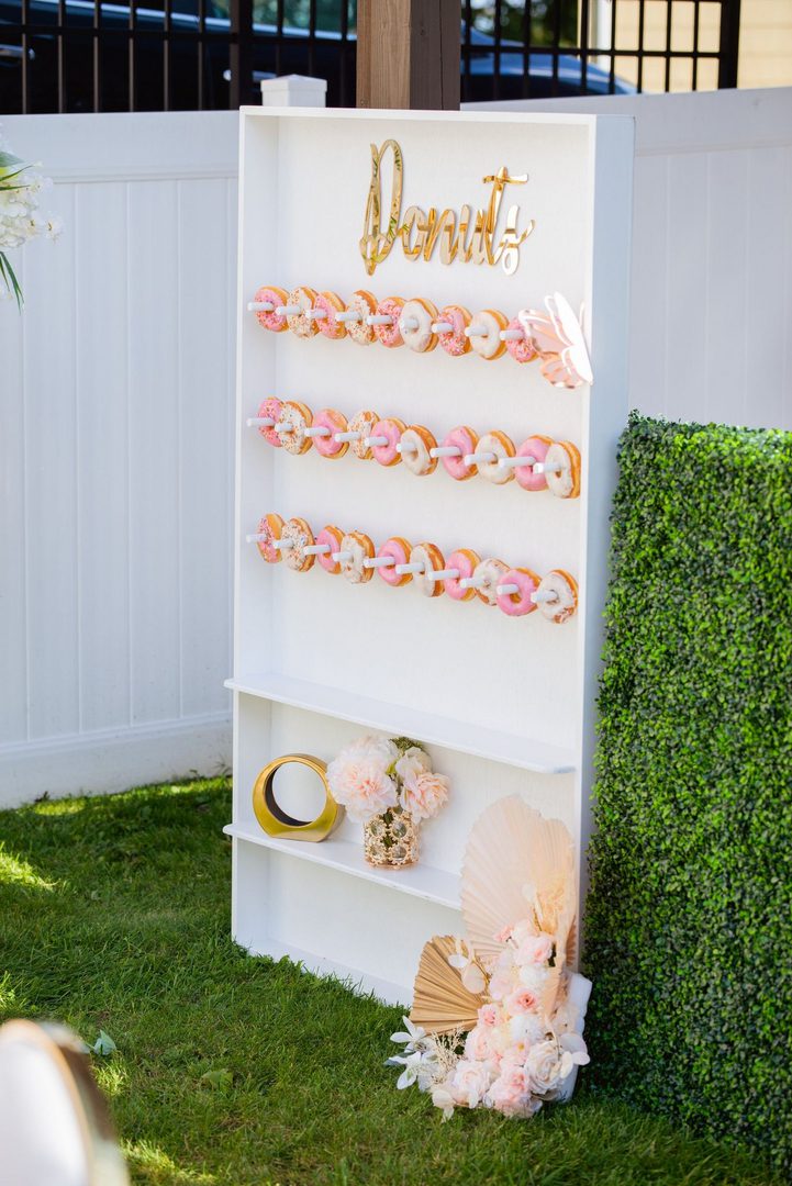 A white display with pink and gold donuts on it.