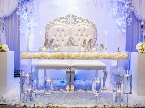 A white wedding table with candles and flowers.